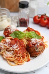 Delicious pasta with meatballs, basil and cheese on light table, closeup