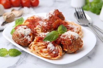 Delicious pasta with meatballs, basil and cheese on white marble table, closeup