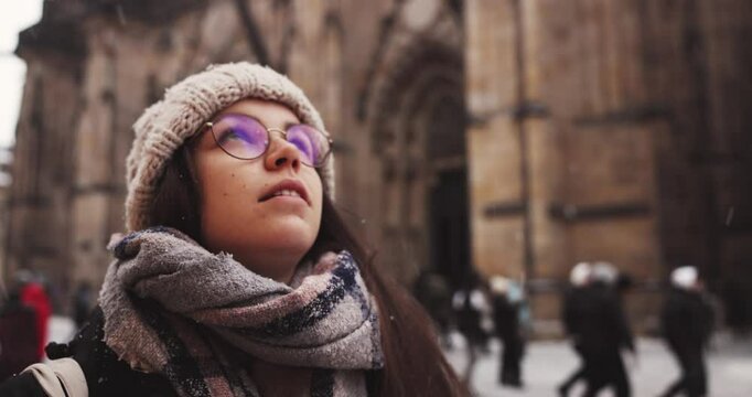 Woman marvels at snowfall near gothic cathedral closeup