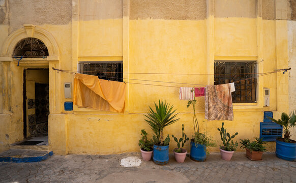 Gold wall with blue plant pots and laundry, El Jadida, Morocco,
