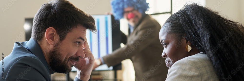 Poster Header of young smiling subordinates looking at one another while making fun of their boss wearing clown wig during presentation