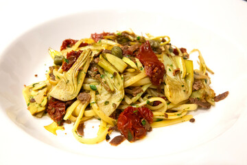 Plato de pasta italiana con alcachofas, tomates, alcaparras y atún