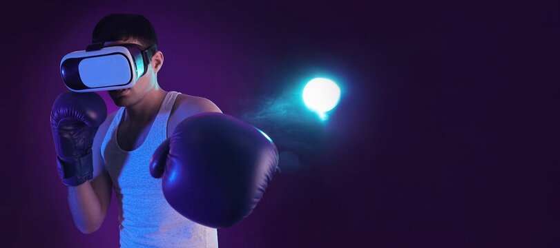 Young wearing VR glasses and boxing gloves on color background with space for text - Powered by Adobe