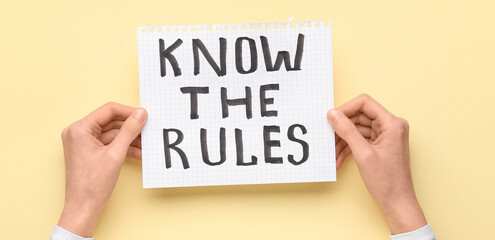 Woman holding paper with text KNOW THE RULES on beige background