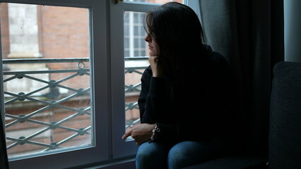 Pensive melancholical woman looking out window thinking