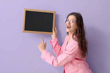 Female teacher pointing at chalkboard on lilac background