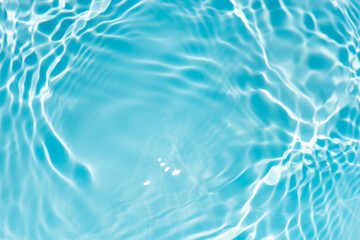 Blue water with ripples on the surface. Defocus blurred transparent blue colored clear calm water surface texture with splashes and bubbles. Water waves with shining pattern texture background.
