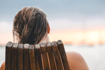 WOMAN ENJOYING THE SUNSET ONE AN WOODEN CHAIR ON AN CARIBBEAN ISLAND - CAYE CAULKER, BELIZE -...