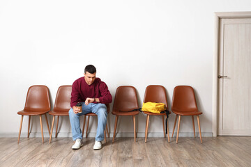 Young man with coffee cup waiting for his turn in room
