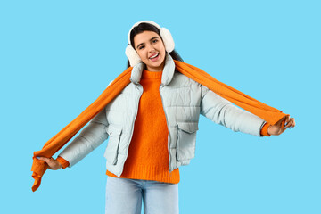 Young woman in winter clothes on blue background