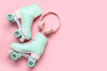 Pair of vintage roller skates and modern headphones on pink background