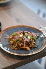 A close-up shot of a traditional Korean dish, Bulgogi, served in a rustic restaurant setting.
