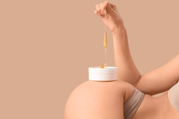 Beautiful young woman holding container with sugaring paste and spatula on brown background, closeup