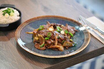 A close-up shot of a traditional Korean dish, Bulgogi, served in a rustic restaurant setting.