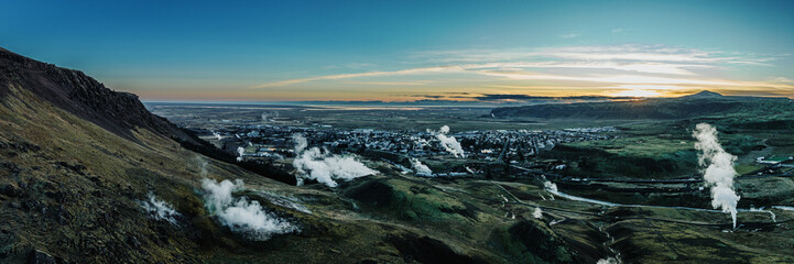 Aerial view of Hveragerdi, South Iceland, showcasing geothermal steam vents and rugged landscapes at dawn.