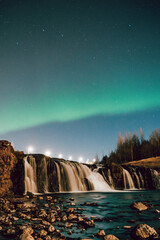 Northern lights illuminating Reykjafoss waterfall in Hveragerdi, South Iceland...