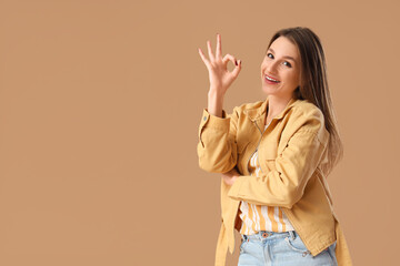 Young woman showing OK on brown background