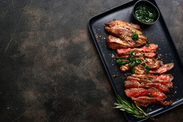 Grilled marbled beef steak on a black plate . Top view with copy space.