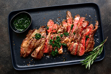 Grilled marbled beef steak on a black plate . Top view with copy space.