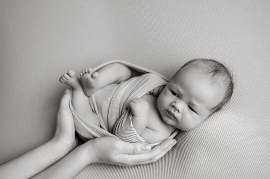 Newborn baby cradled gently in anonymous adult hands