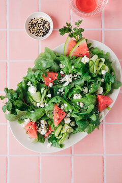 Top view of a fresh ruccola, watermelon, cucumber, and feta salad