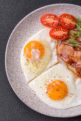 A hearty breakfast with fried eggs, bacon, tomatoes, microgreens