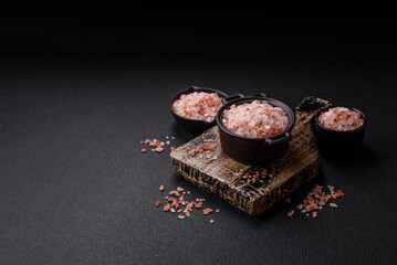 Pink himalayan salt in a black bowl on a dark concrete background