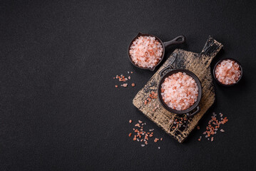Pink himalayan salt in a black bowl on a dark concrete background