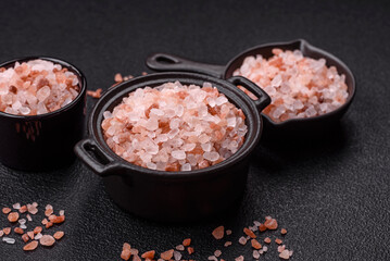 Pink himalayan salt in a black bowl on a dark concrete background