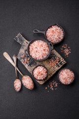 Pink himalayan salt in a black bowl on a dark concrete background