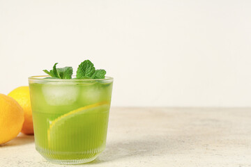 Glass of tasty lemonade with mint on white background