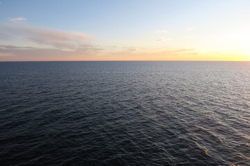 Vom Sonnendeck einer Nachtfähre aus ist der Horizont über dem Skagerrak zu sehen. Die Sonne geht unter und taucht den Himmel in orangefarbenes Licht. Die See ist ruhig.