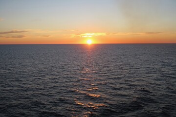Obraz premium Die Sonne geht unter über dem Skagerrak an einem Sommerabend. Die Sonne taucht den Himmel in ein orangefarbenes Licht. Die See ist ruhig. Gesehen von einer Fähre zwischen Oslo und Kopenhagen.