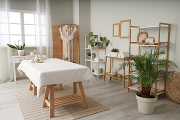 Interior of light spa salon with massage couch, shelf units and tables