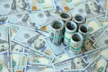 Fototapeta premium Many rolls of one hundred dollar bills lies on big amount of american currency banknotes