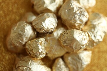 Small pile of golden nuggets on shiny gold glitter background