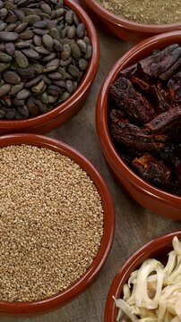 Ingredients for homemade vegan Mexican sauce Pipian Tlatonile: toasted sesame seeds (unhulled) and pumpkin seeds, toasted dried chilies, epazote, and salt. Table spin. Vertical video.