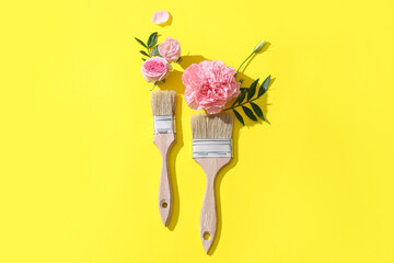 Composition with brushes for painting and beautiful flowers on yellow background