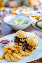 Gourmet sliders with fries and wine.