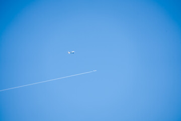 Airbus A380 and a twin engined jet liner aircraft in deep blue sky, contrails vapour trails