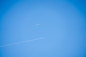 Airbus A380 and a twin engined jet liner aircraft in deep blue sky, contrails vapour trails