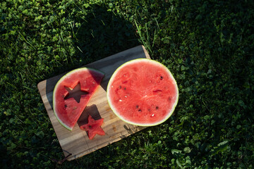 Refreshing and delicious slices of watermelon are cut into fun star shapes and placed on a wooden board outdoors