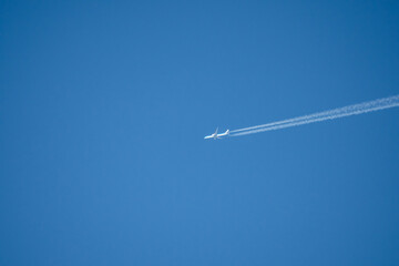 twin engined jet liner aircraft in deep blue sky, contrails vapour trails
