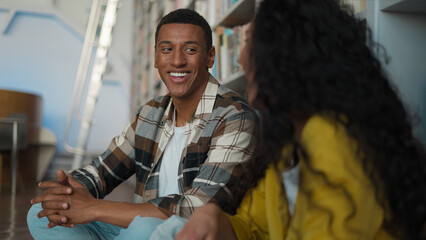 African American man Caucasian Hispanic woman students learning sitting together floor talking...