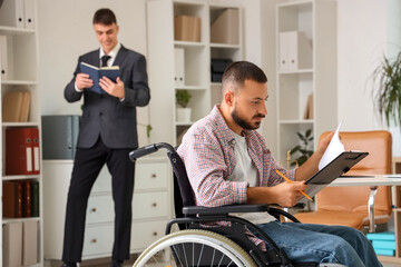 Young man in wheelchair reading document at lawyer's office