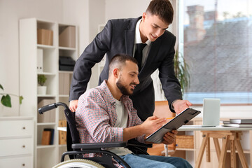 Young lawyer with man in wheelchair signing document at office