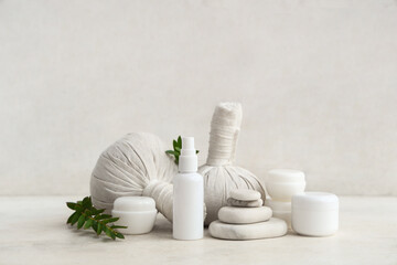 Set of cosmetic products, spa stones, massage bags and plant branches on light background