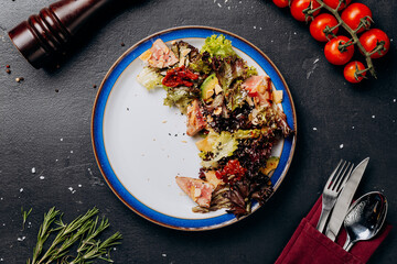 Fresh tuna salad with mixed greens, avocado, and sun-dried tomatoes on a vibrant blue plate