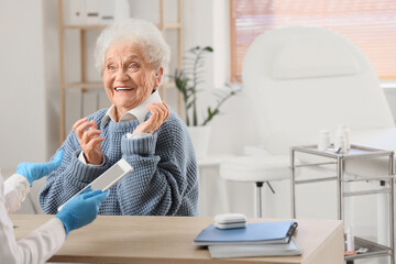 Fototapeta premium Senior woman with hearing aid visiting doctor in clinic