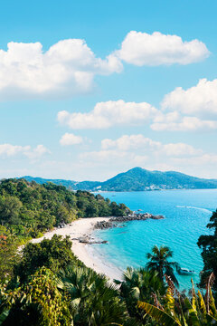 A scenic view of sandy beach and a long sea against blue sky with cloud with sunlight and the trees background in summer, breathtaking scenery in Laem Sing Viewpoint, Phuket , Thailand. Vertical.